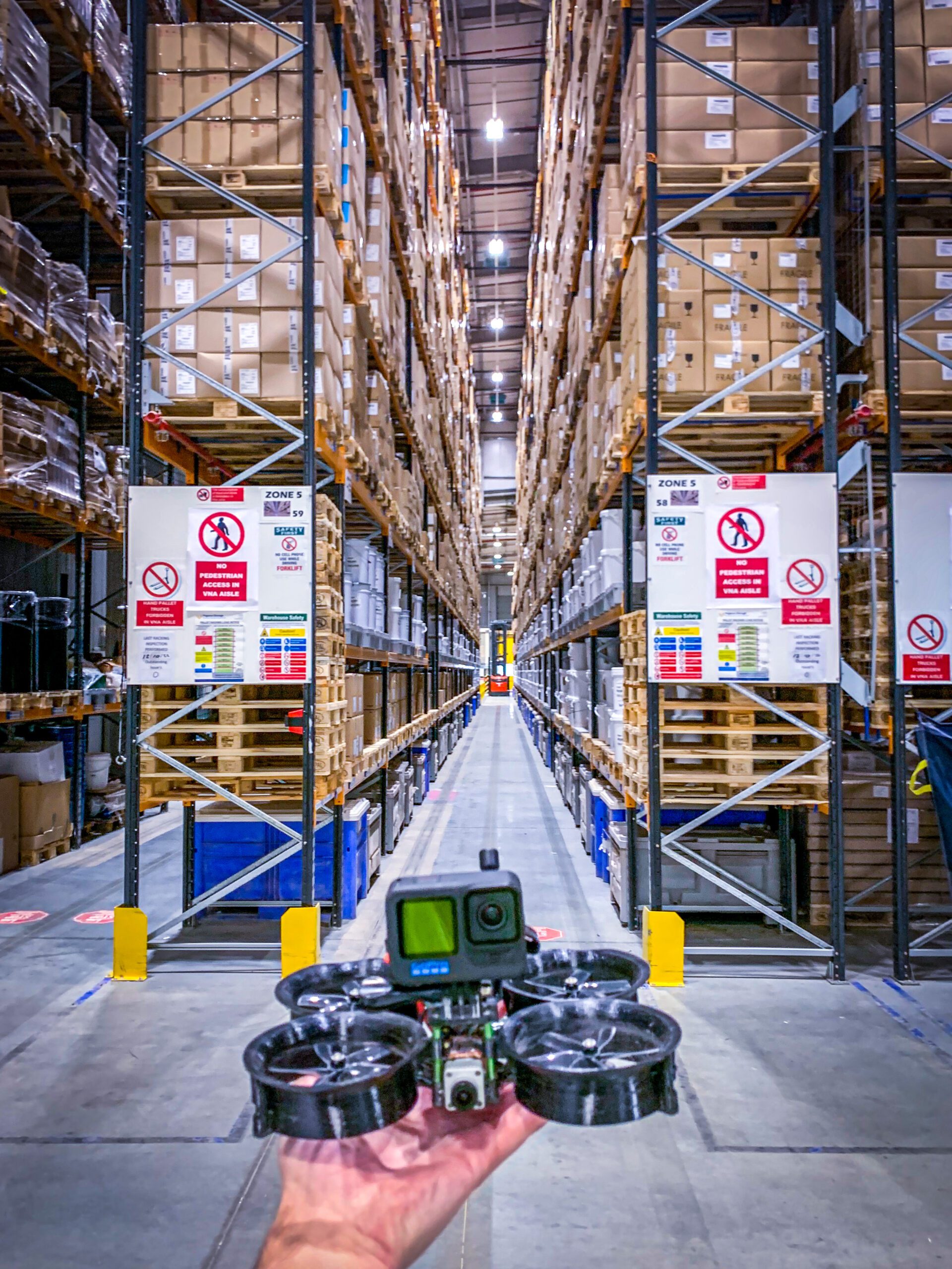 Image of a small FPV drone with a large warehousing space in the background